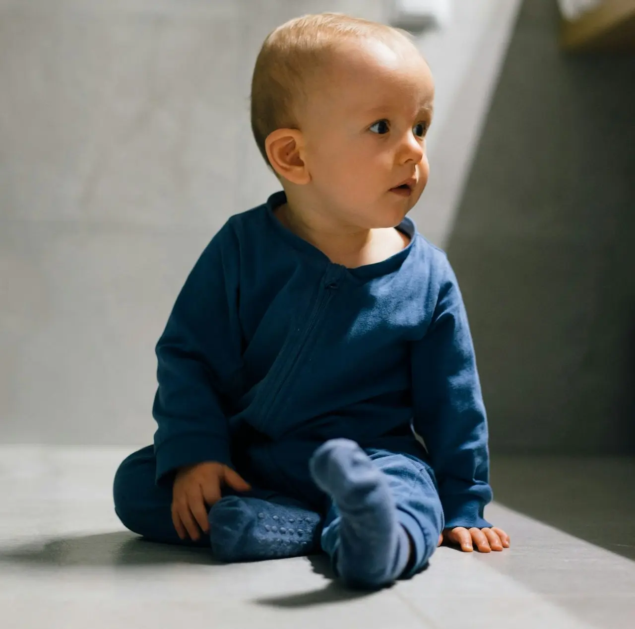 baby in blue long sleeve shirt and blue denim jeans sitting on floor