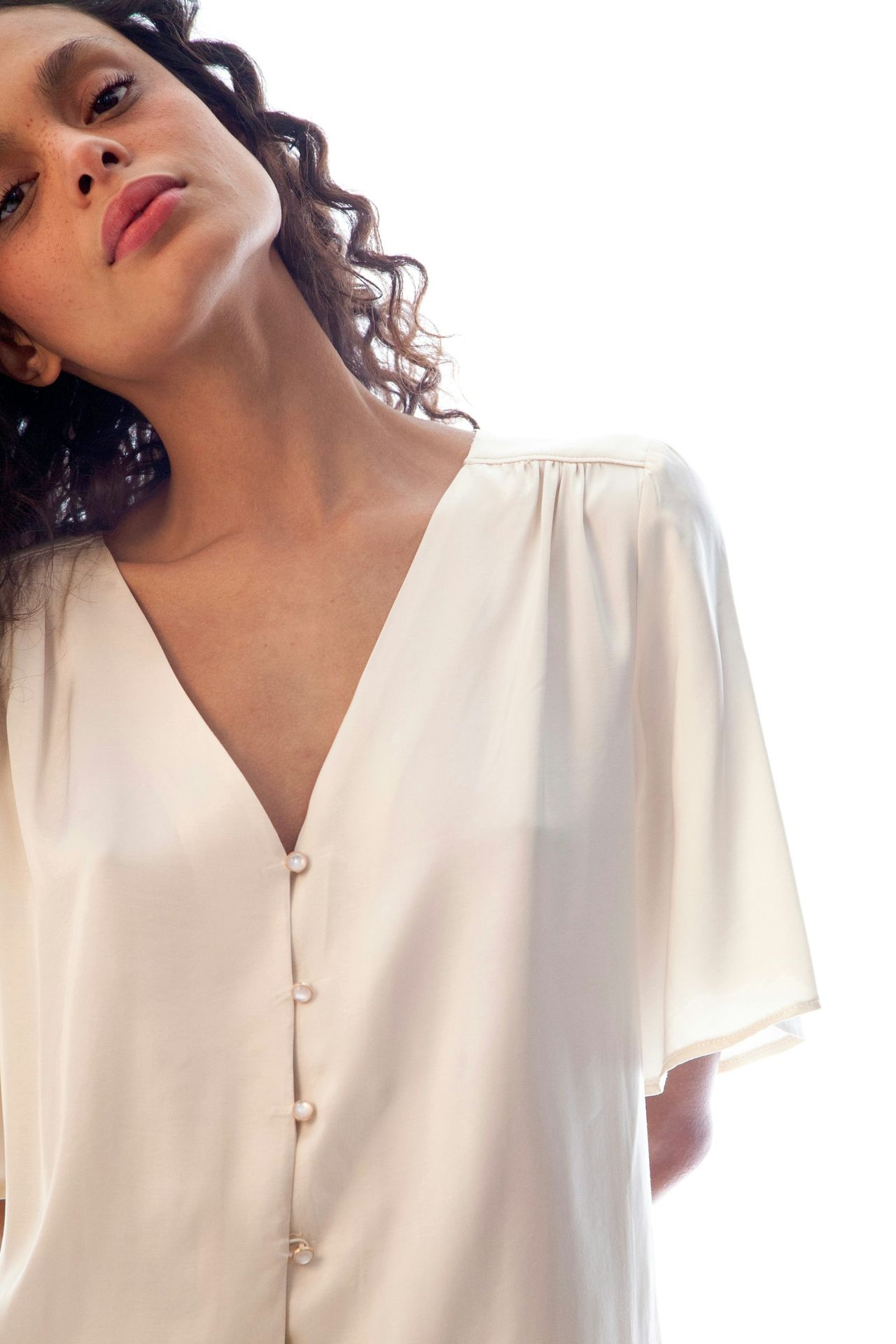 a woman with curly hair wearing a white blouse