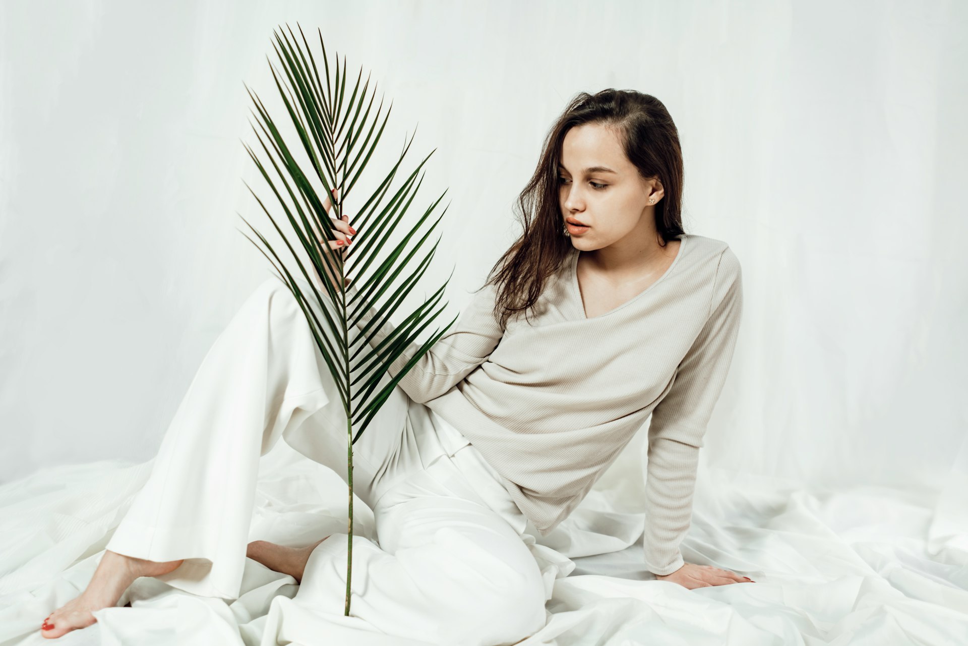 a woman sitting on a bed holding a palm tree
